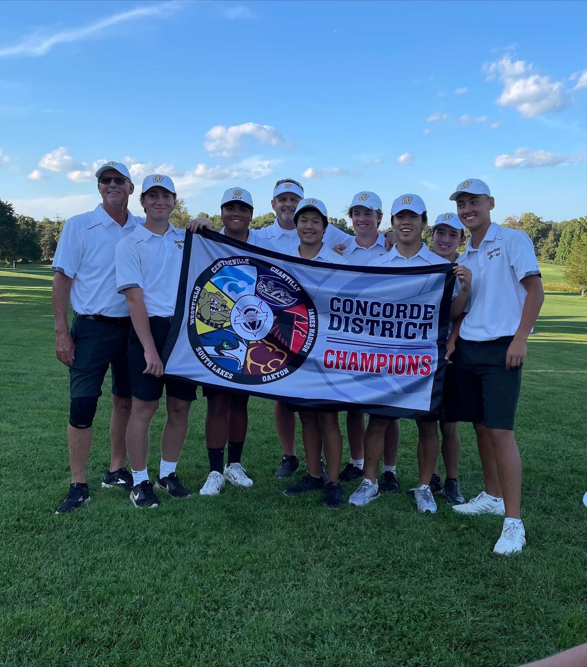Golf team members pose with the district championship banner 